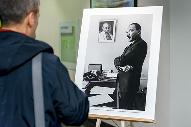 A guest looks at one of the black and white photos of the Black Star Collection which features civil rights leader, Dr. Martin Luther King Jr. in his office with a picture of Mahatma Gandhi, champion of nonviolent civil disobedience, hanging on the wall. Photo credit: Clifton Li.