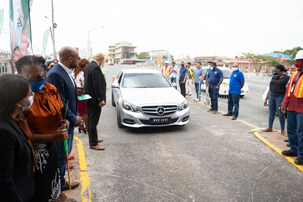 Minister of Public Works, Bishop Juan Edghill and others watch on as a vehicle utilises the automated tolling system. Photo credit: GDPI.
