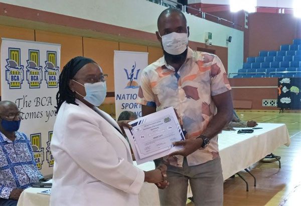 Omarie Taitt receives his certificate, for the Groundsmen training course, from Permanent Secretary, Ministry of Youth, Sports and Community Empowerment, Yolande Howard. Photo credit: F. Belgrave/BGIS.
